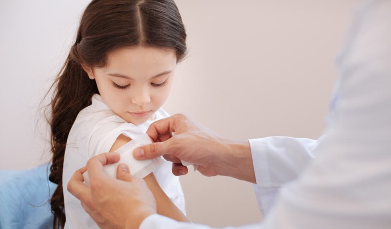 Medical professional placing band-aid on young girl