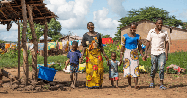 A group of three adults and two children, hand in hand, walking